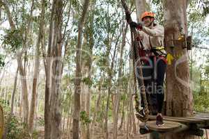 Woman wearing safety helmet getting ready to climb on zip line