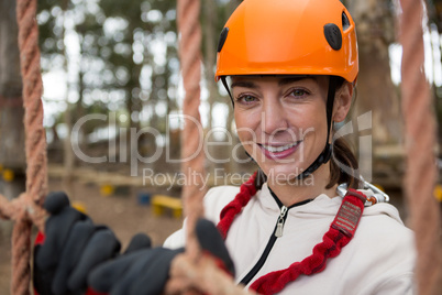 Portrait of smiling woman posing through a rope fence in the forest