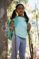 Little girl standing with backpack holding walking sticks in her hands