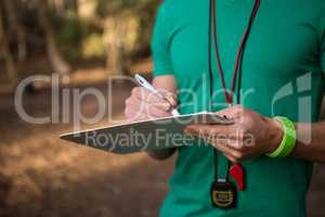 Trainer holding notepad in his hands in the forest on a sunny day