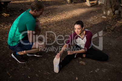 Woman performing stretching exercise with the help of trainer