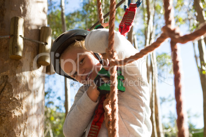 Little girl wearing helmet standing on rope fence