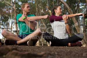 Woman performing stretching exercise with the help of trainer