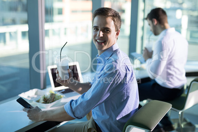 Portrait of male executive using mobile phone while having drink