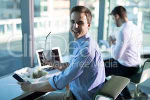 Portrait of male executive using mobile phone while having drink