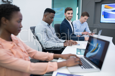 Male and female executives using laptop during meeting