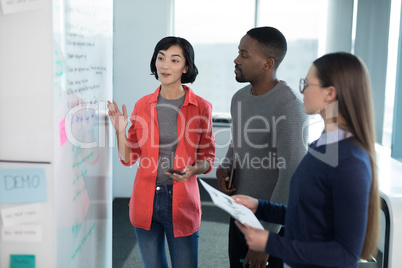 Male and female executives discussing on whiteboard