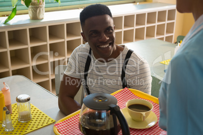 Waitress serving black coffee to man