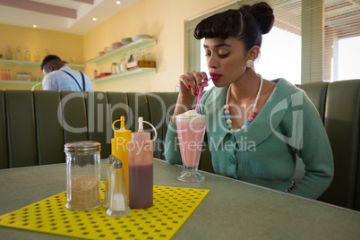 Woman having milkshake at restaurant