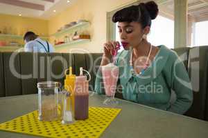 Woman having milkshake at restaurant