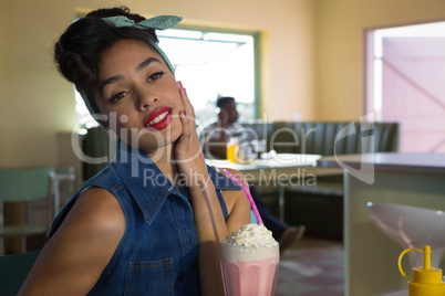 Thoughtful woman looking away while having milkshake