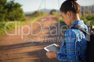 Young woman with backpack holding tablet