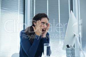 Shocked female executive looking at desktop pc
