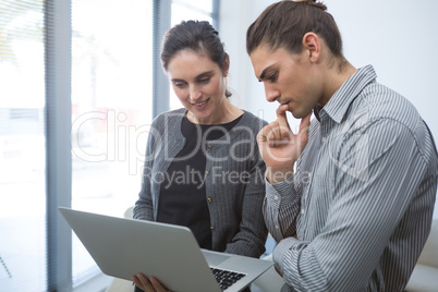 Colleagues discussing over laptop in waiting area