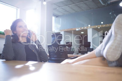 Female executive relaxing at desk while talking on mobile phone Female executive relaxing at desk while talking on mobile phone