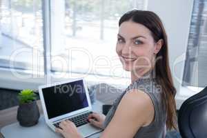 Portrait of confident female executive using laptop at desk