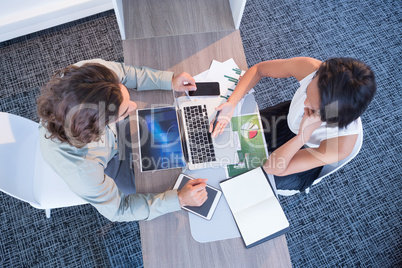 High angle view of business executives discussing over laptop