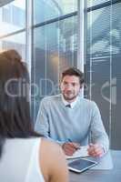 Male executive writing in organizer during meeting