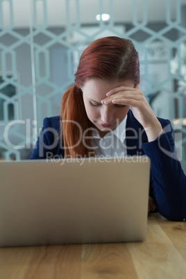 Tensed businesswoman sitting with laptop at desk