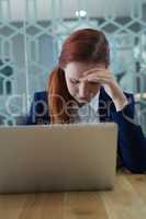 Tensed businesswoman sitting with laptop at desk