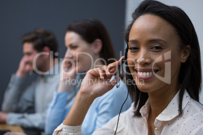 Business executives with headsets using computers at desk