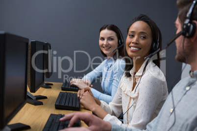 Business executives with headsets using computers at desk