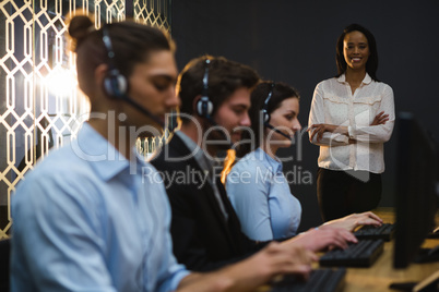 Business executives with headsets using computers at desk