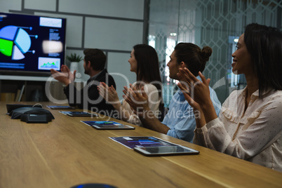 Business colleagues clapping hands in meeting