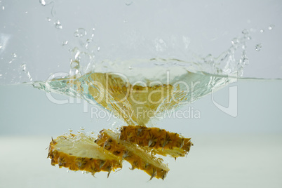 Slices of pineapple falling into the water