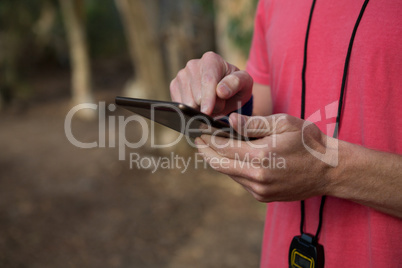 Trainer using his tablet on a sunny day in the forest