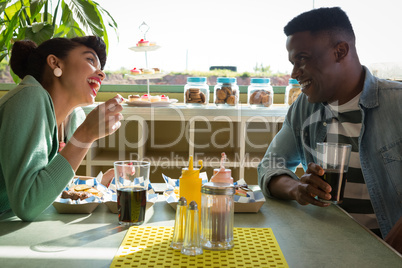 Smiling couple interacting with each other while having food