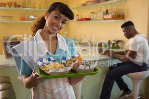 Waitress holding breakfast while man working on laptop