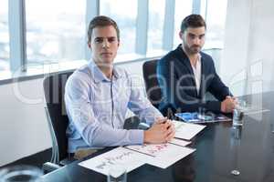 Portrait of male executives sitting at desk