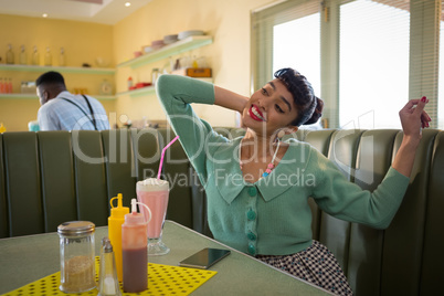 Smiling young woman sitting on couch stretching her arms