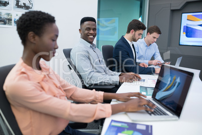 Male and female executives using laptop during meeting