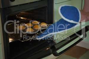 Woman putting muffins in oven