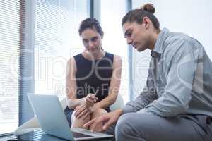 Colleagues discussing over laptop in waiting area