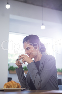 Thoughtful female executive having coffee at table