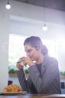 Thoughtful female executive having coffee at table