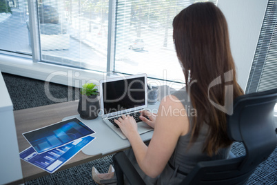 Rear view of female executive using laptop at desk