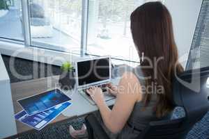 Rear view of female executive using laptop at desk