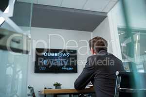 Rear view of businessman watching television