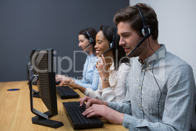 Business executives with headsets using computers at desk