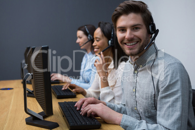 Business executives with headsets using computers at desk