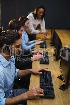 Business executives with headsets using computers at desk