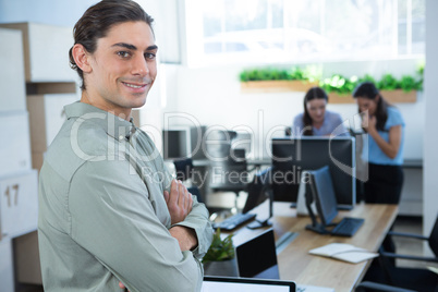 Male executive looking at camera with folded hands in the office