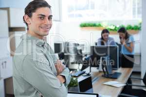 Male executive looking at camera with folded hands in the office