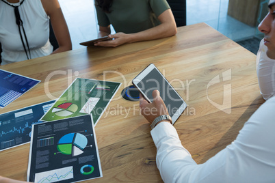 Executive using tablet with business graph on table