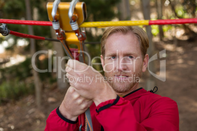 Young hiker man holding zip line pulley in the forest during daytime