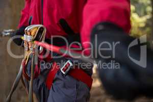 Man harness tied along with zip line in the forest on a sunny day